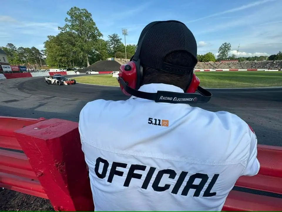 Race officials inspecting a stock car during post-race teardown at Bowman Gray Stadium