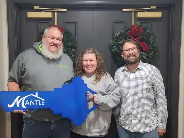 Happy buyer holding Mantle Realty key after closing