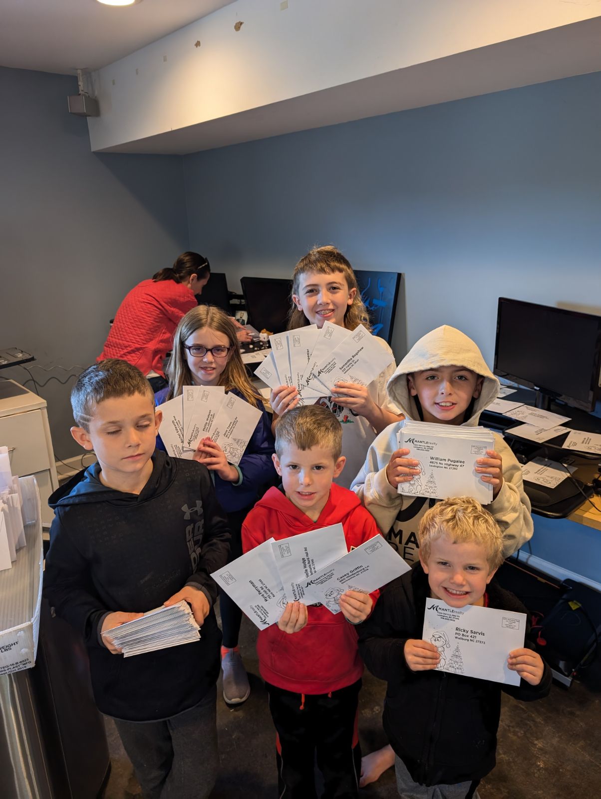 Mantle kids helping stuff envelopes for Christmas cards