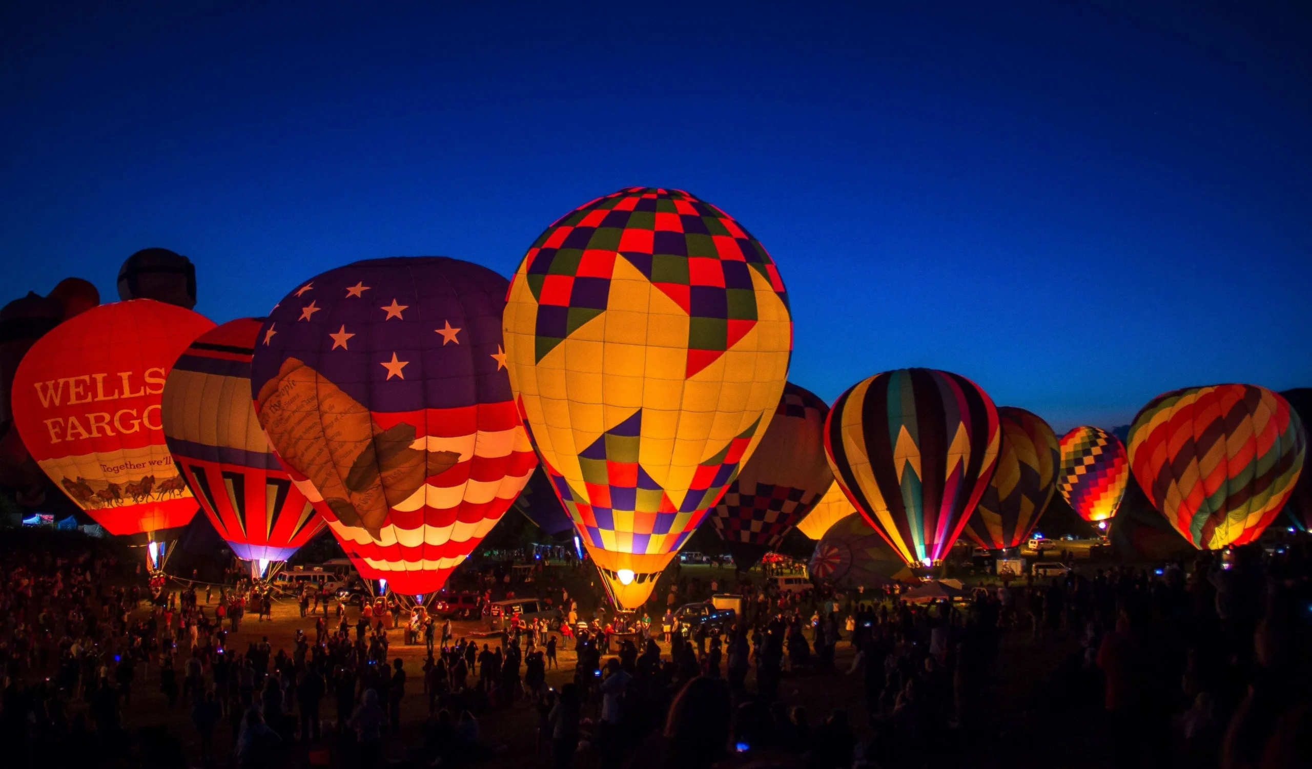 Carolina BalloonFest evening glow at Statesville Regional Airport, dozens of lit hot air balloons and crowds after dark